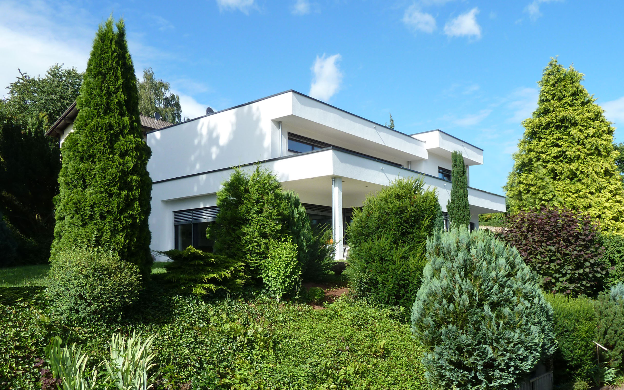 Leben mit Kunst – Gartenansicht der Villa mit gestaffelten Terrassen und altem Baumbestand