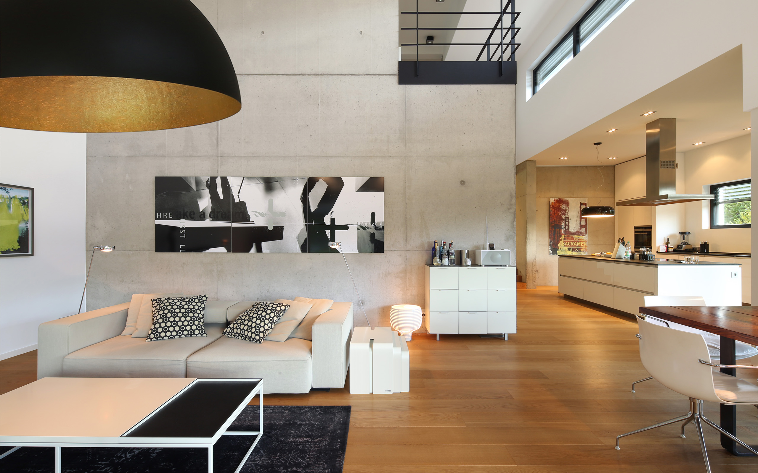 Leben mit Kunst – Wohnbereich mit weißer Sofalandschaft und offener Küche