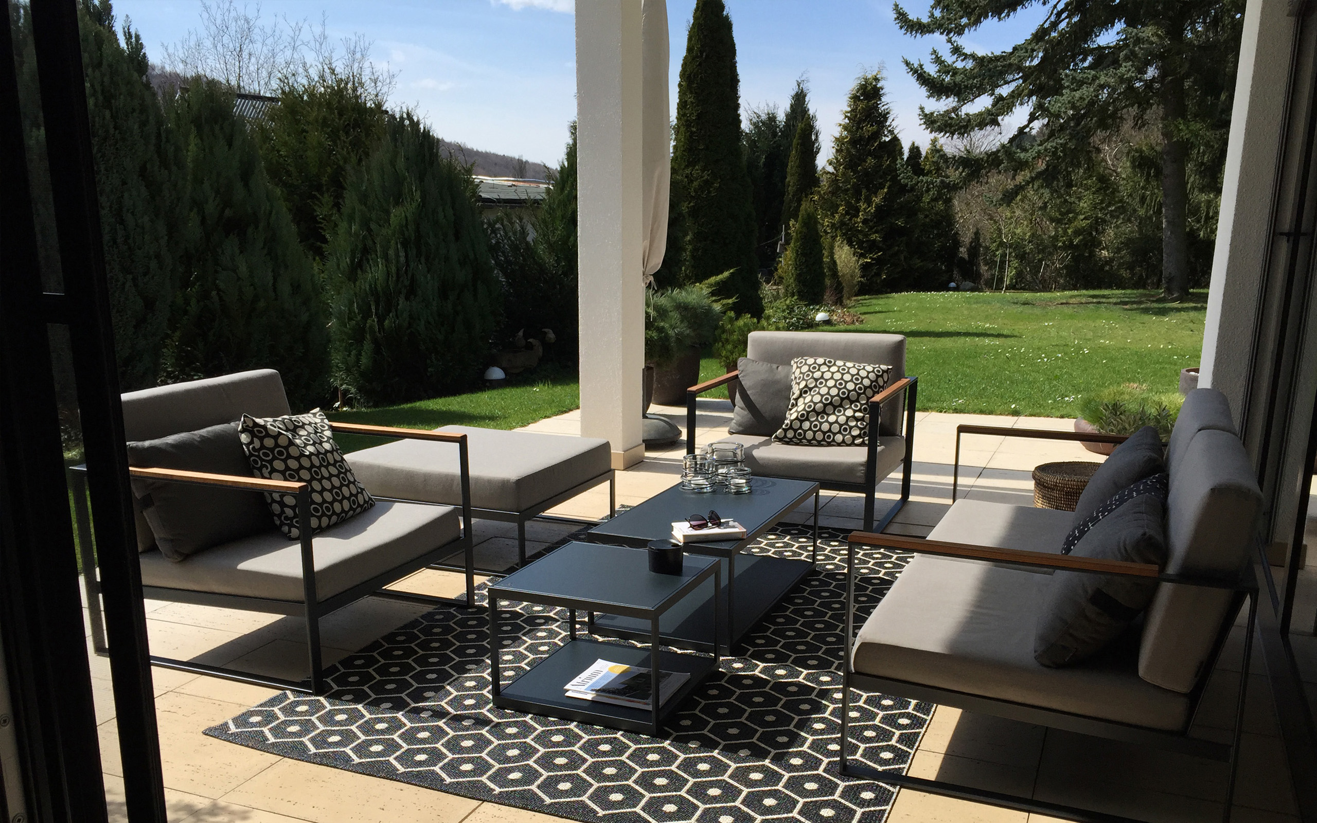 Leben mit Kunst – überdachte Terrasse mit Loungemöbeln und Gartenblick
