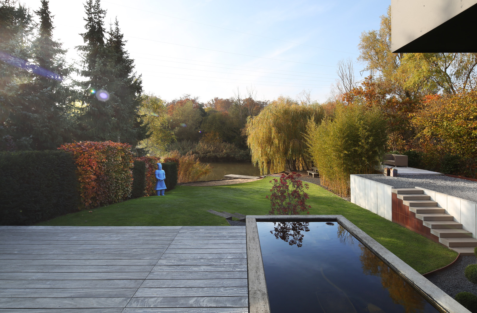 Haus am See – Holzdeck mit langgestrecktem Wasserbecken im herbstlichen Garten