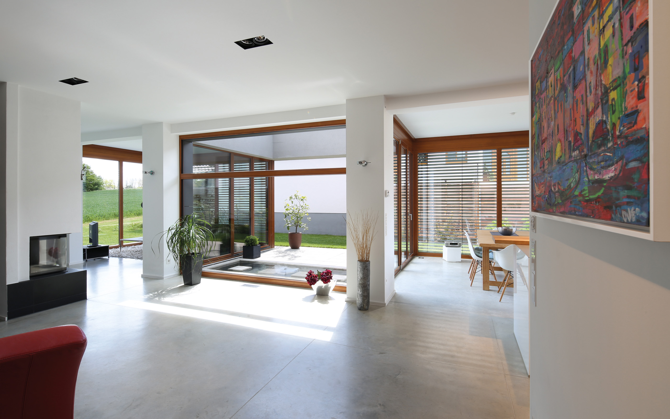 Aus- und Einblick – Wohnraum mit Fensterfront, Kamin und Kunst