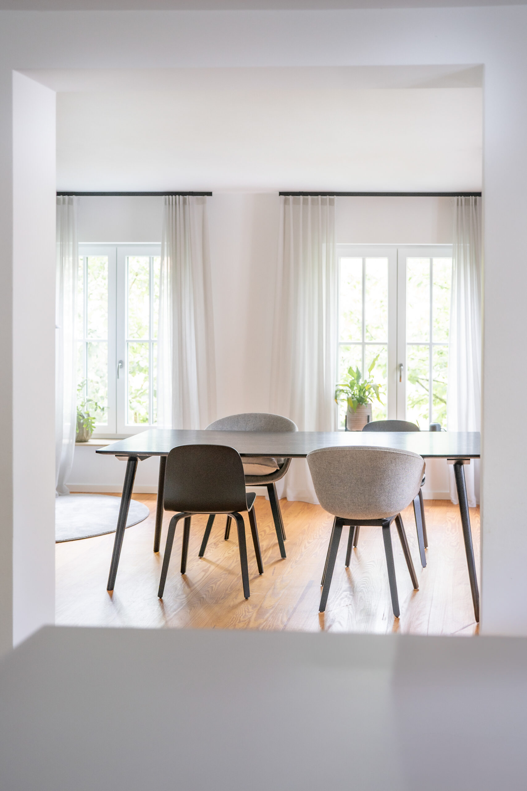 Haus BB – Esszimmer mit schwarzem Tisch und hellen Polsterstühlen