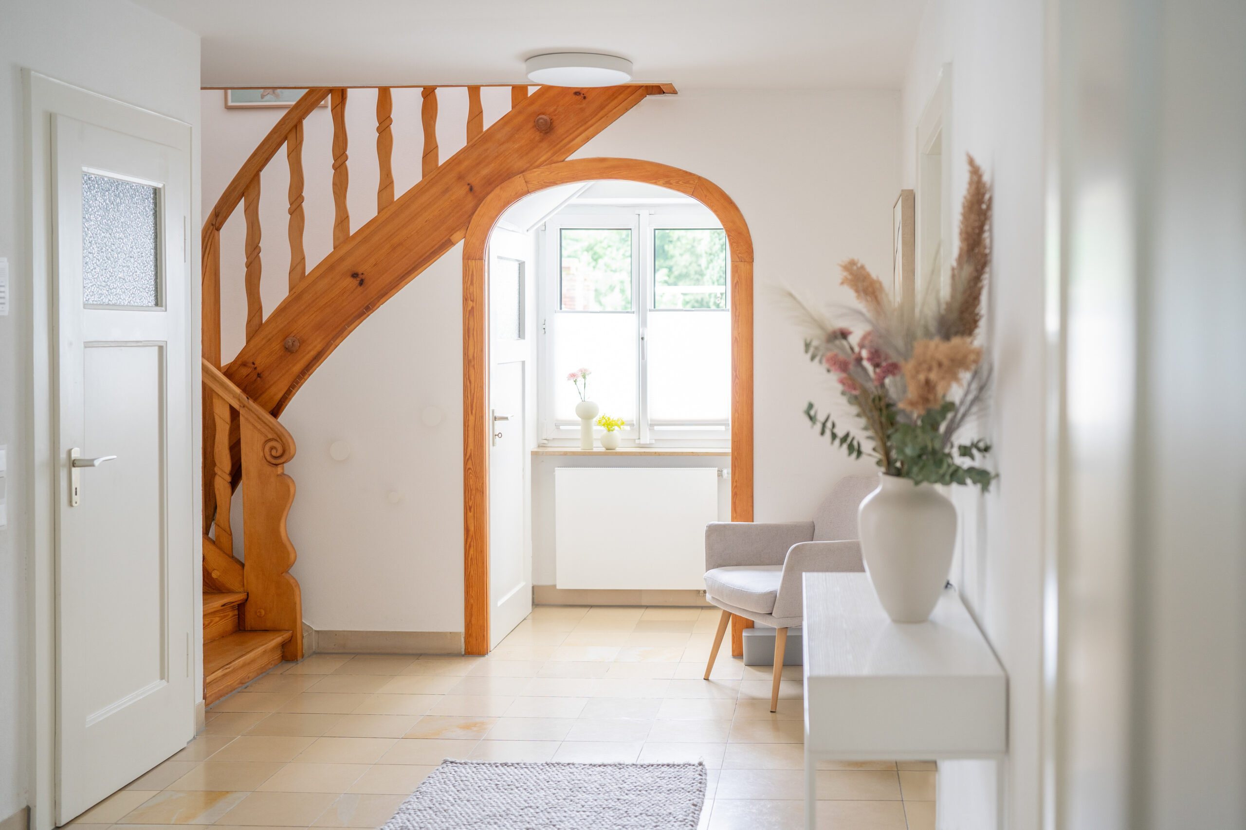 Haus BB – Diele mit historischer Holztreppe und Rundbogen