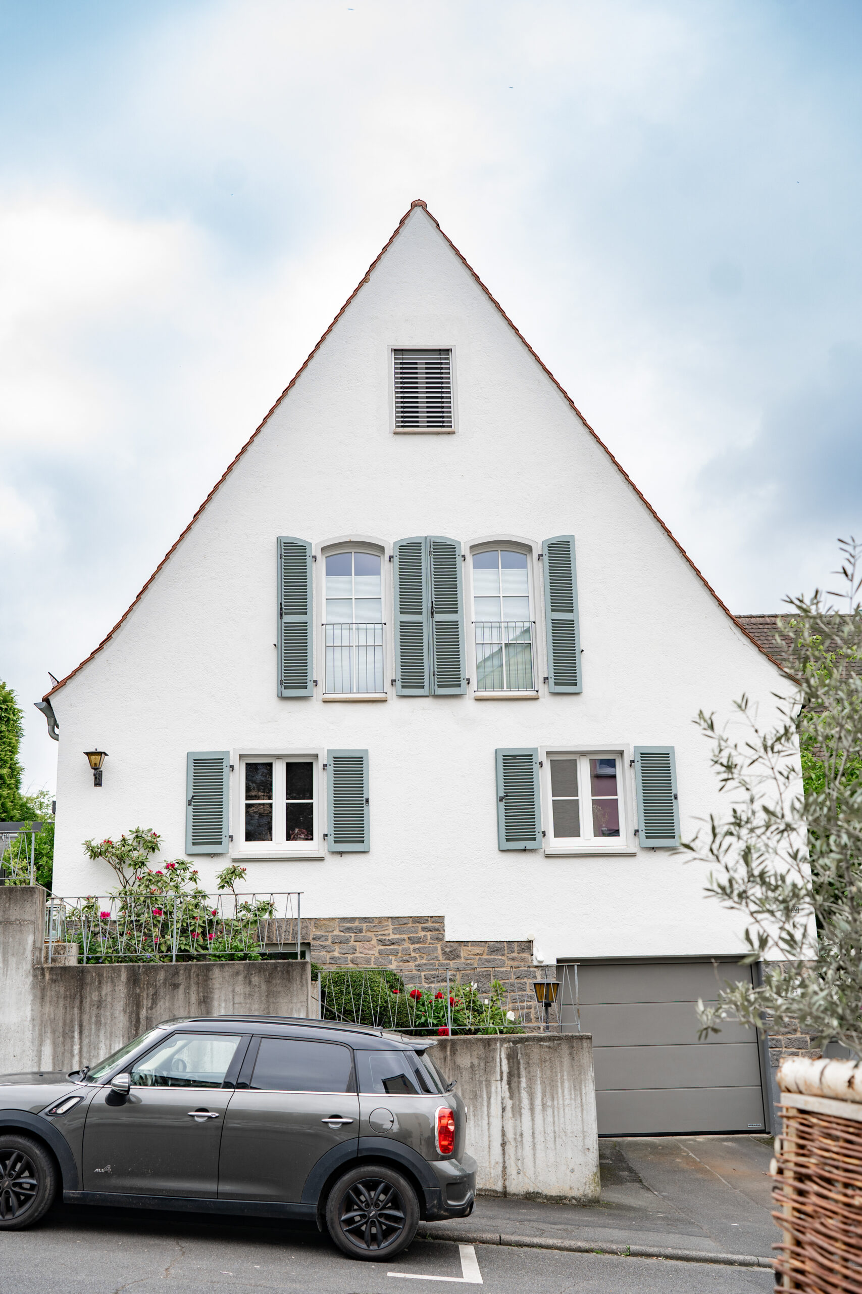 Haus BB – Giebelansicht des weißen Altbaus mit grünen Fensterläden