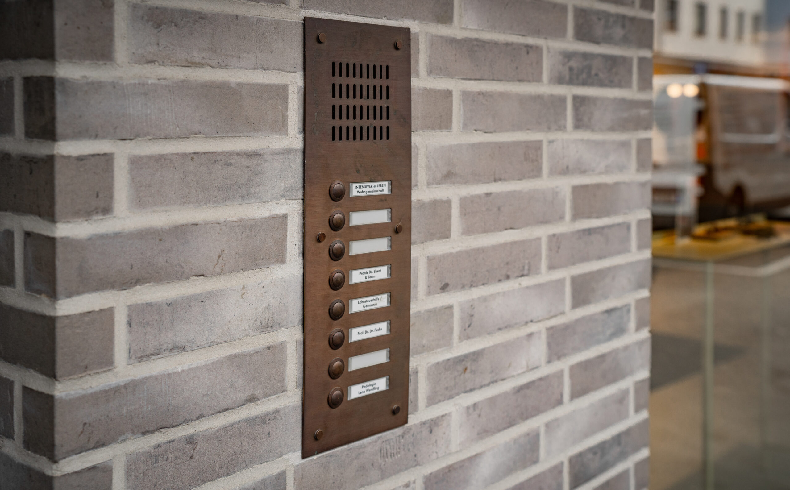 Geschäftshaus GH & BO – Detail der bronzefarbenen Klingelanlage im Klinkermauerwerk