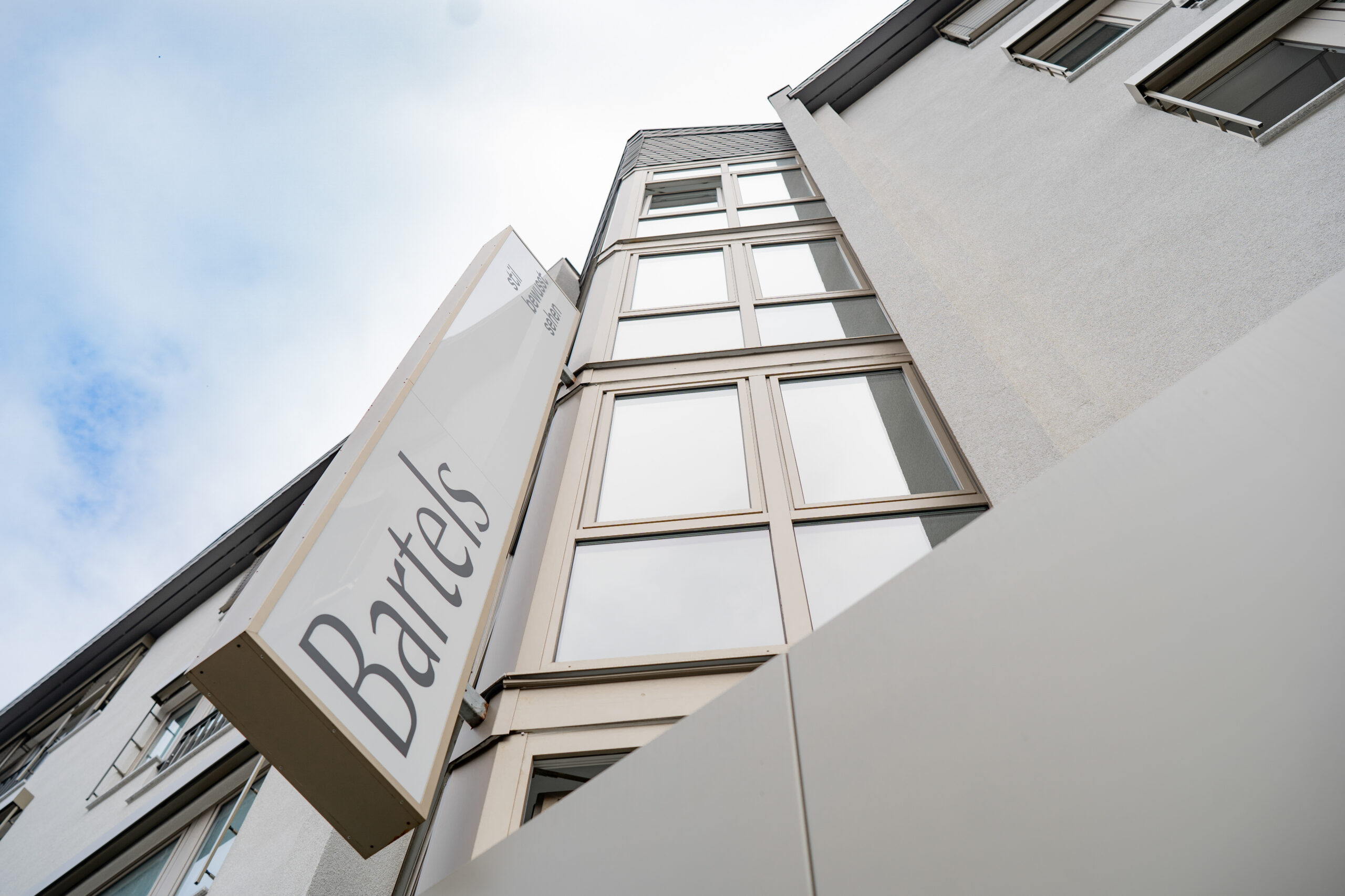 Geschäftshaus GH & BO – Blick nach oben auf Fassade und Fahnenschild