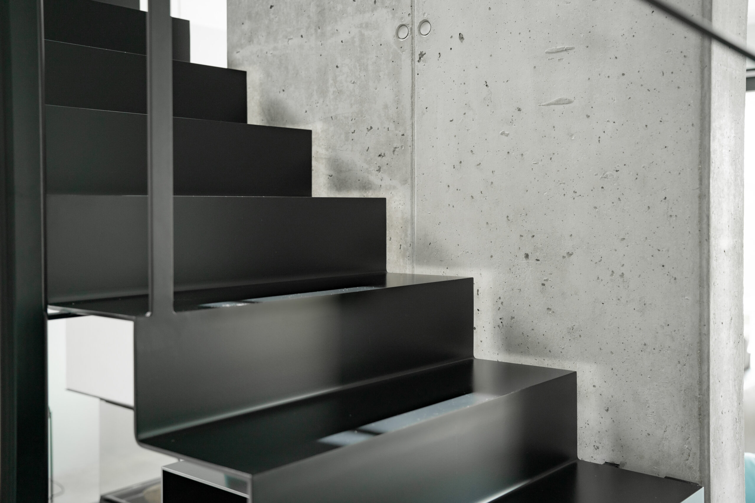 Haus LGW – Detail der schwarzen Stahltreppe an der Sichtbetonwand