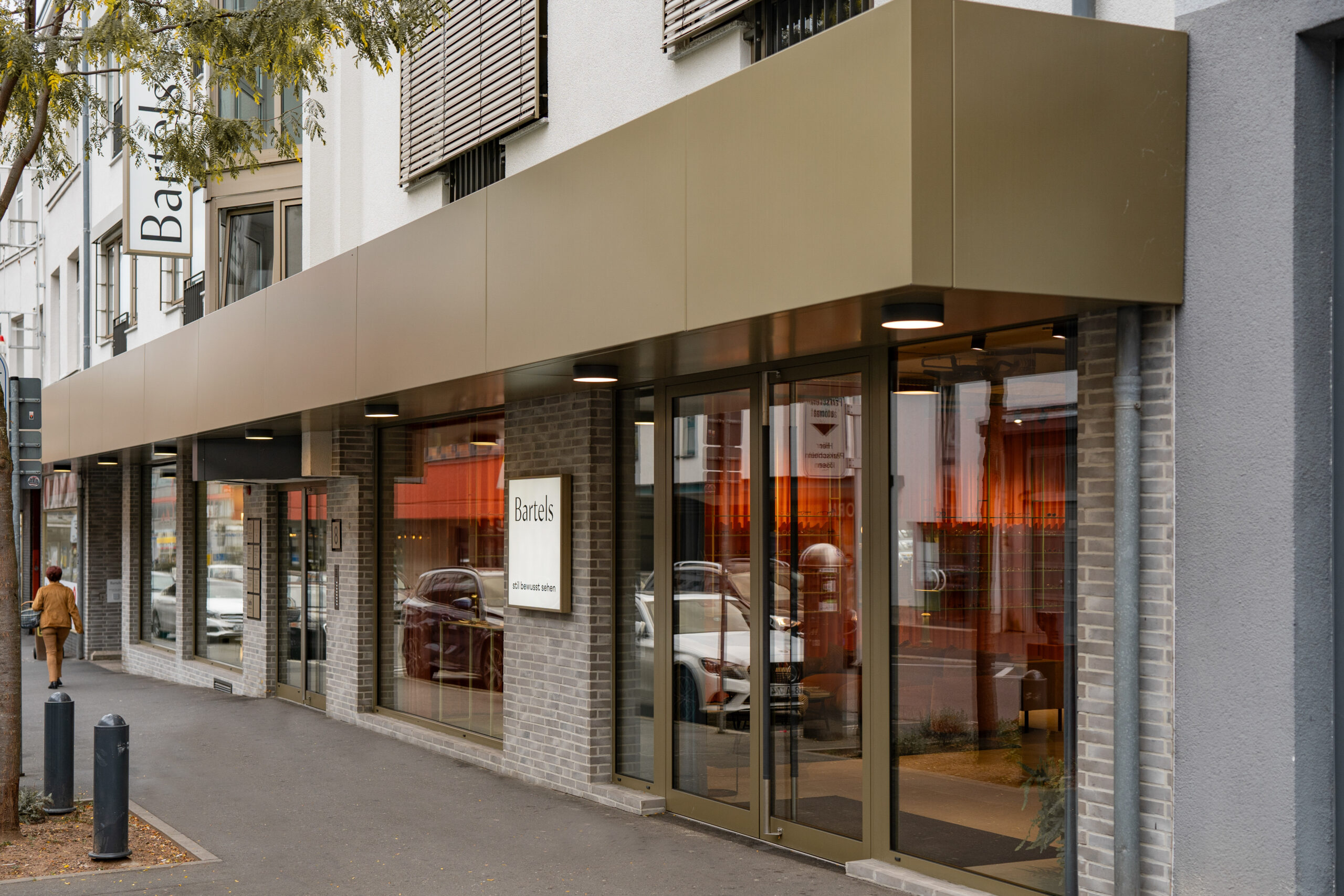 Geschäftshaus GH & BO – lange Schaufensterfront mit auskragendem Vordach entlang der Straße