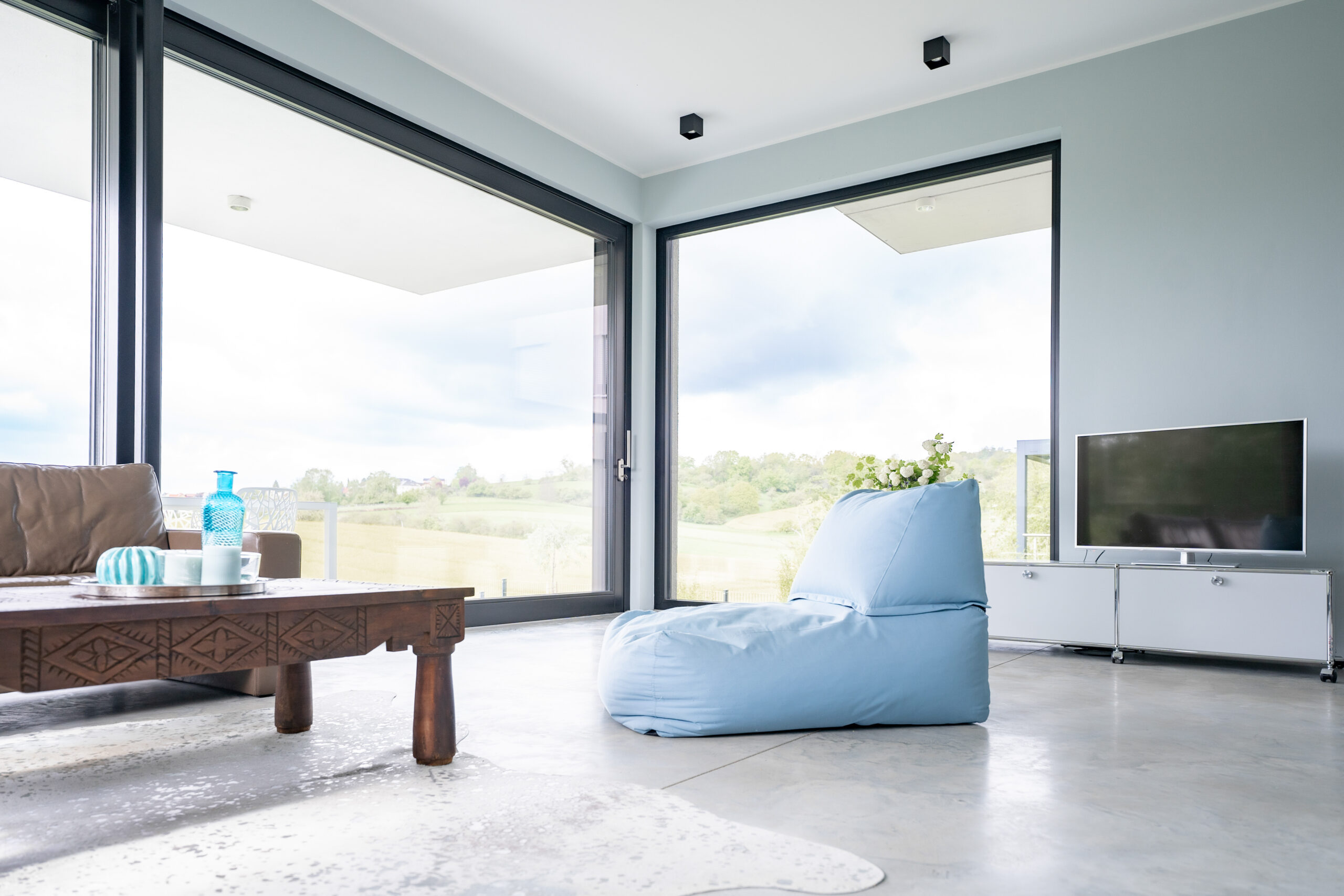 Haus LGW – Wohnzimmer mit Eckverglasung und Blick in die Felder