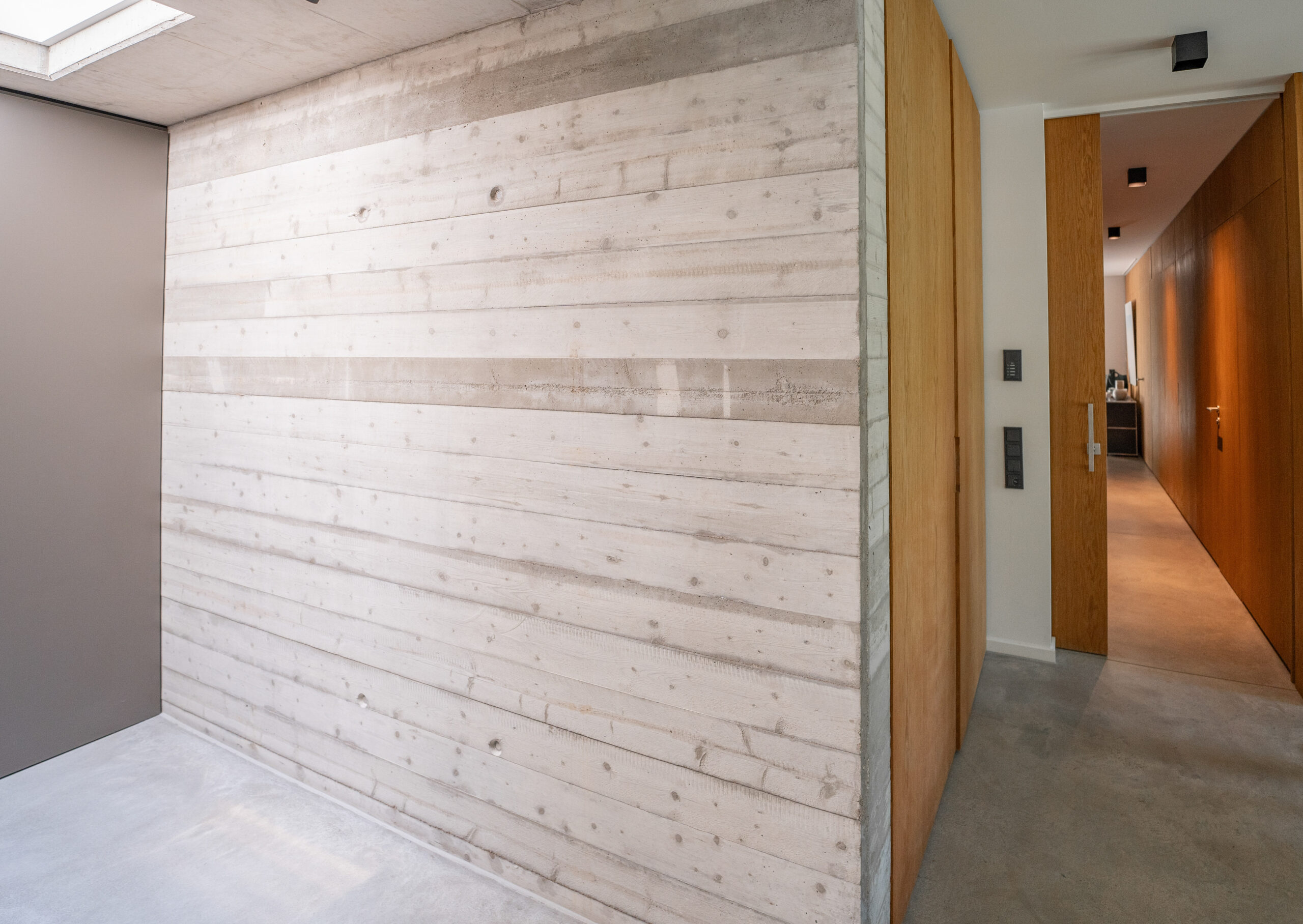 Haus WIE – Flur mit Sichtbetonwand in Brettschalung und Holzeinbauten