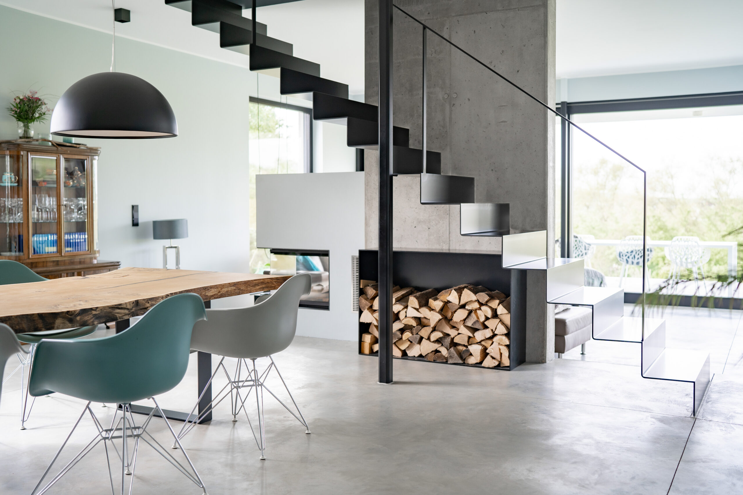 Haus LGW – Essplatz mit Massivholztisch unter der schwarzen Stahltreppe