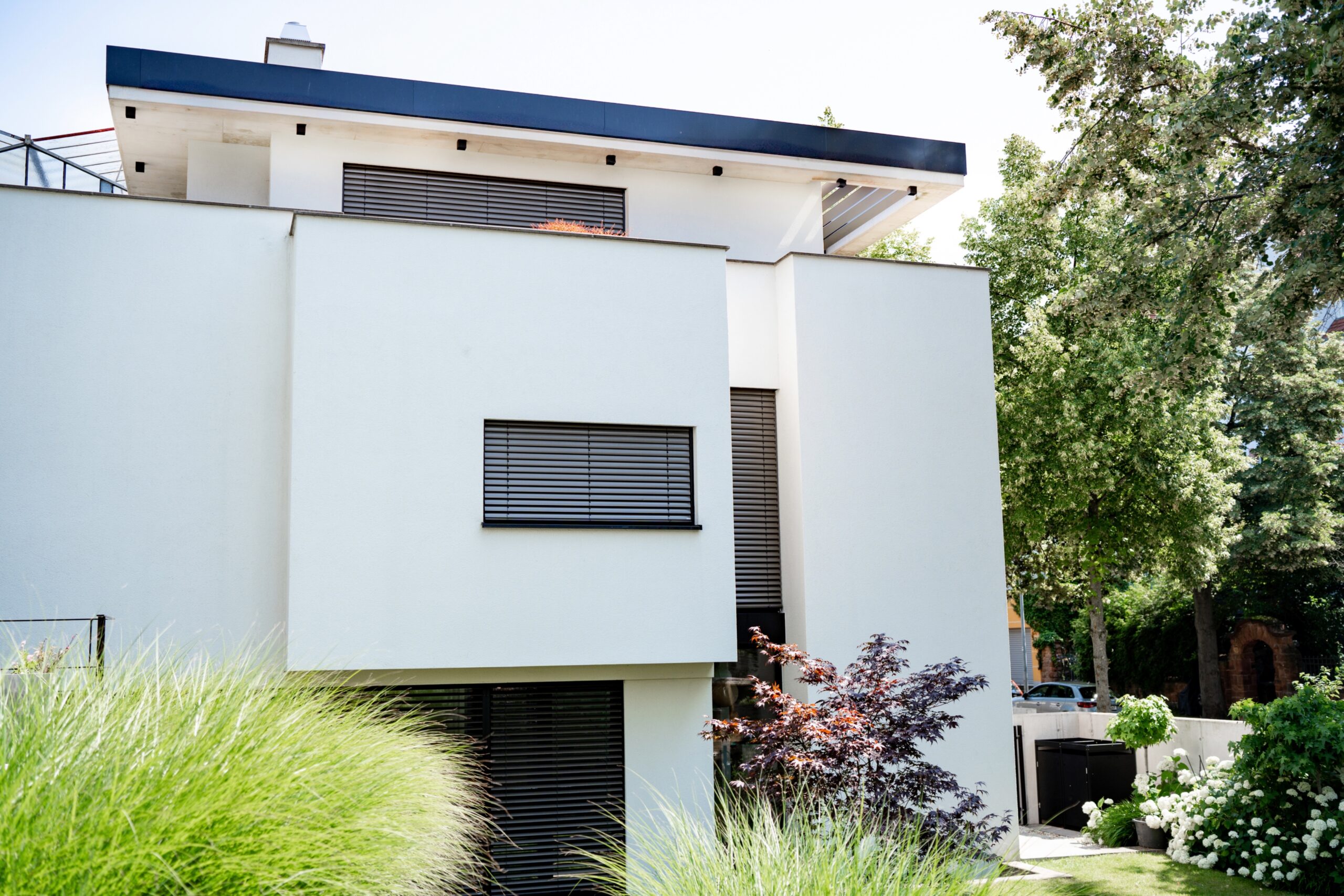 Haus WIE – Gartenfassade mit gestaffelten weißen Baukörpern und Gräsergarten
