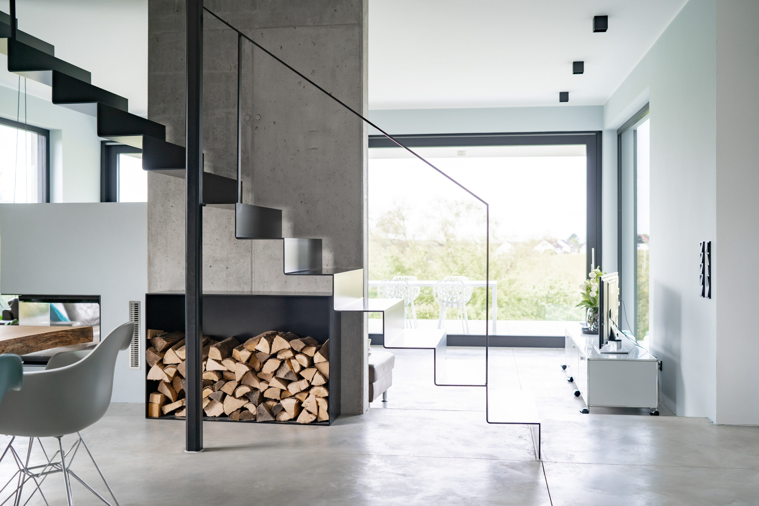 Haus LGW – offener Wohnraum mit freistehendem Kamin und Stahltreppe