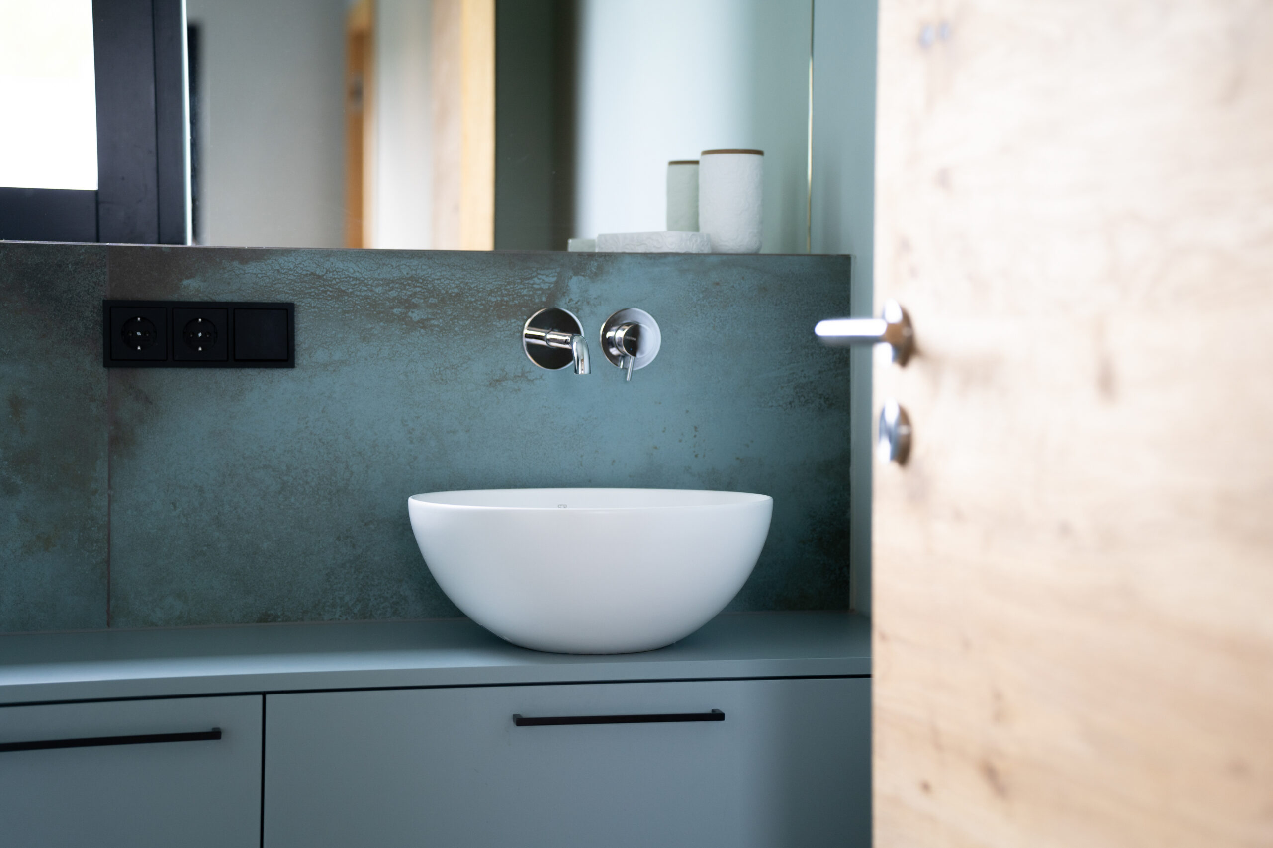 Haus LGW – Gäste-WC mit weißem Aufsatzbecken und Holztür